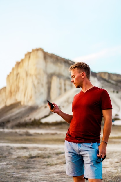 El hombre usa un teléfono inteligente en los últimos rayos del sol