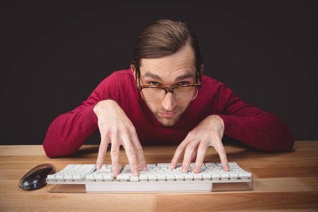 Hombre usando anteojos escribiendo en el teclado de la computadora