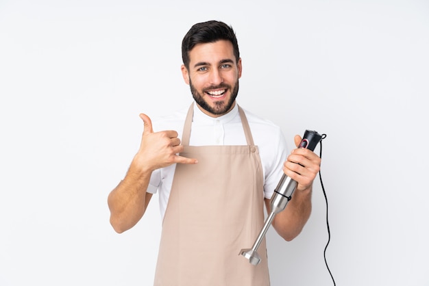 Hombre usando la batidora de mano en blanco haciendo gesto de teléfono