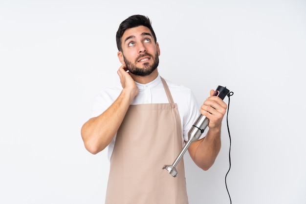 Hombre usando la batidora de mano en blanco pensando en una idea