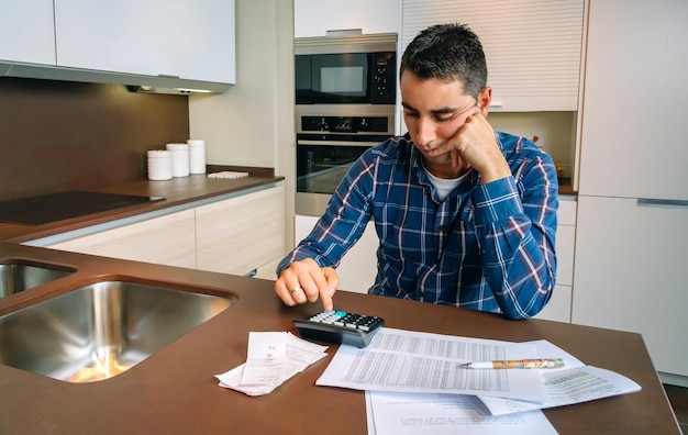 Foto hombre usando calculadora por los papeles en la mesa en casa