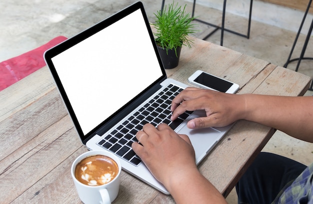 hombre usando la computadora portátil y el café en la mesa de madera