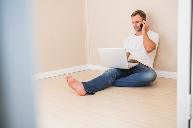 Hombre usando la computadora portátil y hablando por teléfono