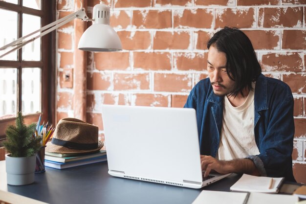 Foto hombre usando una computadora portátil mientras está sentado en la mesa en la oficina