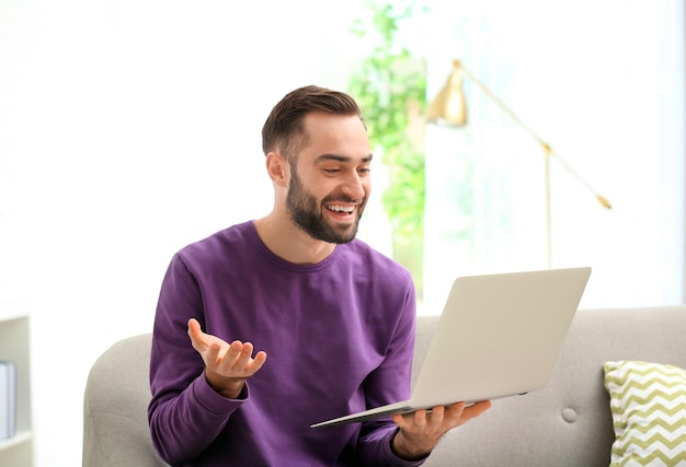 Hombre usando una computadora portátil para video chat en la sala de estar