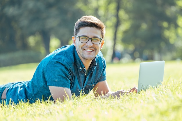 Hombre usando laptop en el parque de la ciudad