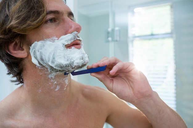Hombre usando una navaja para afeitarse la barba