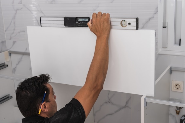 Hombre usando un nivel de burbuja para instalar una unidad de cocina