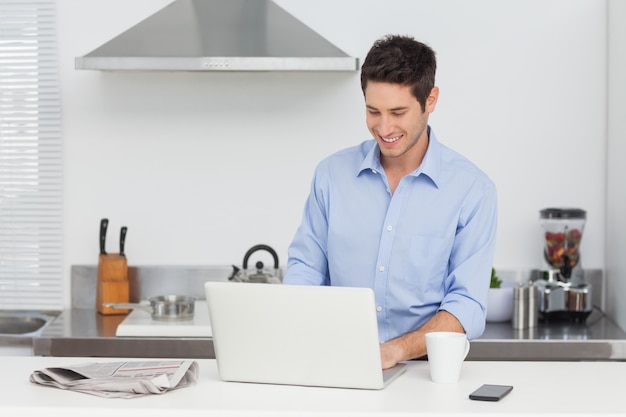 Hombre usando una PC portátil en la cocina