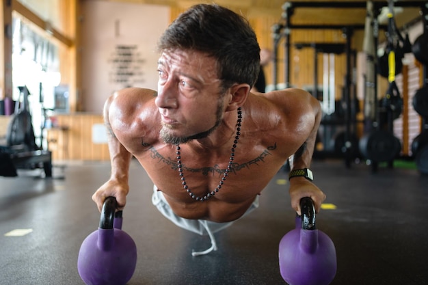 Hombre usando pesas rusas para hacer flexiones en un gimnasio