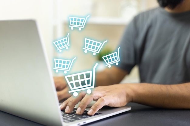 Hombre usando portátil compras en línea icono del carrito de compras en la pantalla compra pago en internet supermercado en línea gadget venta y pago del cliente