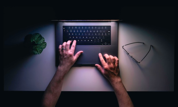 Hombre usando portátil en el lugar de trabajo nocturno vista superior