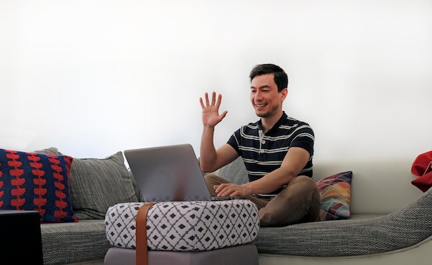 Hombre usando portátil mientras está sentado en el sofá en casa