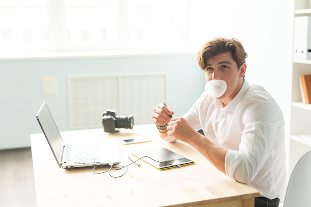 Foto hombre usando portátil en taza de café en la mesa