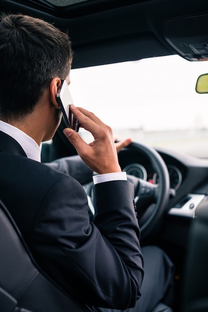 Hombre usando su teléfono mientras conduce el auto