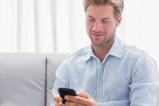 Hombre usando su teléfono en un sofá