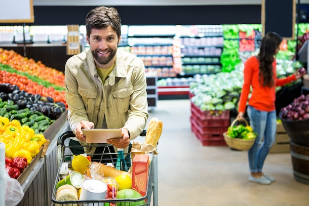 Hombre usando tableta digital mientras compras en el supermercado