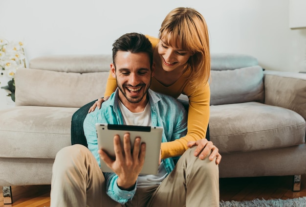 Hombre usando tableta digital mientras está sentado con su novia en casa