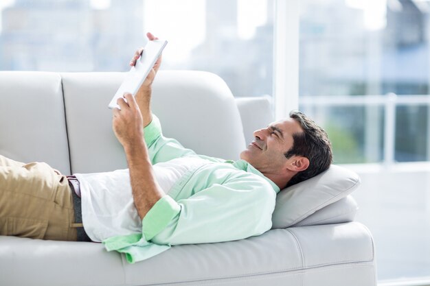 Hombre usando tableta digital mientras se relaja en el sofá