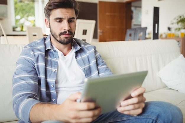 Hombre usando tableta digital mientras se relaja en el sofá