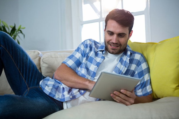 Hombre usando tableta digital mientras se relaja en el sofá