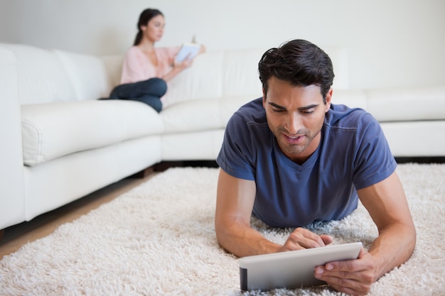 Hombre usando una tableta mientras su novia está leyendo un libro