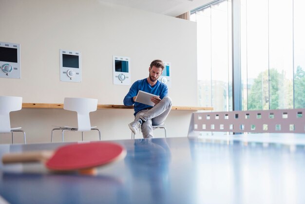 Hombre usando tableta en la sala de descanso de la oficina moderna