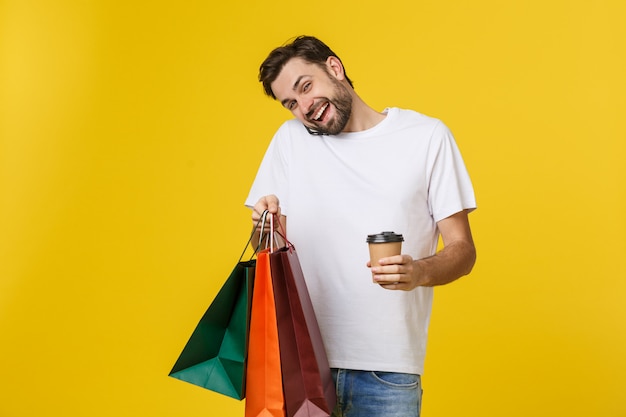 Foto hombre usando un teléfono celular con bolsas de compras.