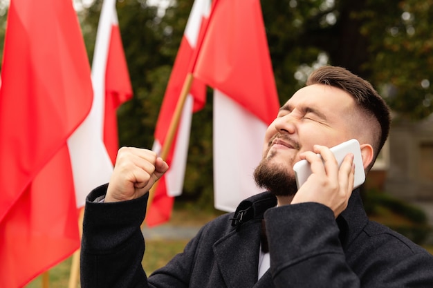 Hombre usando un teléfono inteligente con banderas de Polonia detrás