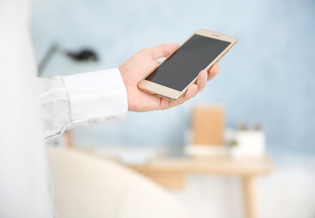 Hombre usando un teléfono inteligente en el fondo interior de la habitación borrosa