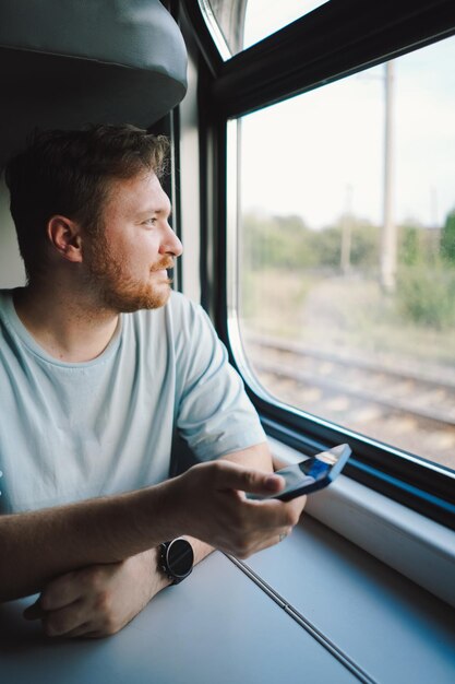 Un hombre usando un teléfono inteligente mientras viaja en tren