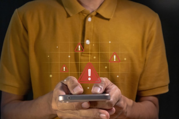 Hombre usando un teléfono inteligente con un triángulo rojo señal de advertencia de precaución en la pantalla virtual para la notificación de error contenido restringido o concepto de mantenimiento