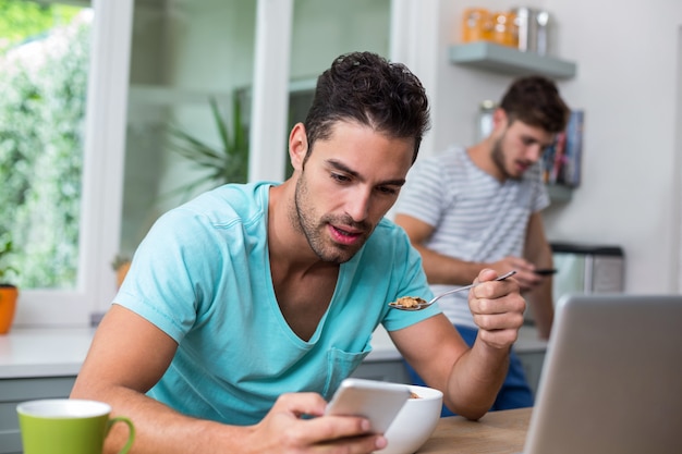 Hombre usando el teléfono mientras tiene comida en la mesa