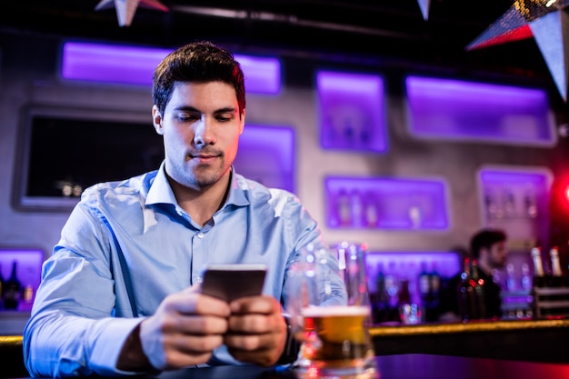 Hombre usando un teléfono móvil en barra de bar