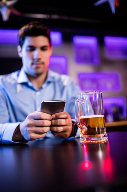 Hombre usando un teléfono móvil en barra de bar