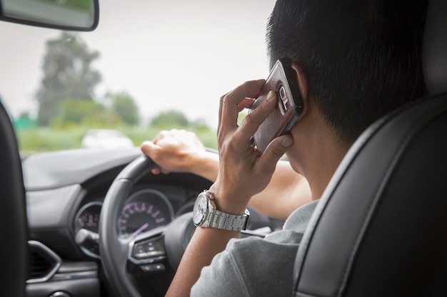 Hombre usando teléfono móvil hablando un rato conduciendo un auto