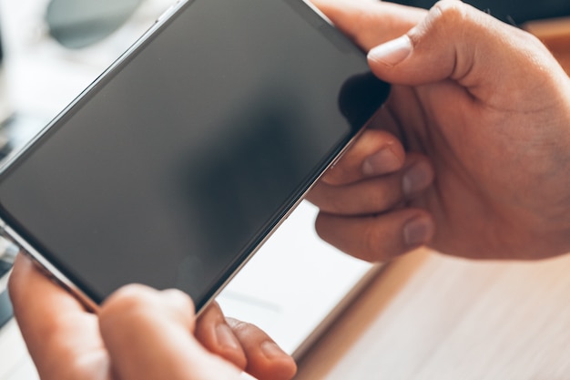 Hombre usando teléfono móvil inteligente. Manos del hombre de negocios usando el teléfono celular en el escritorio de oficina.