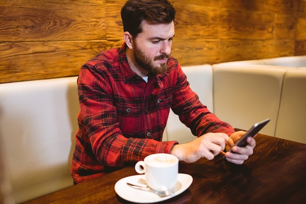 Hombre usando un teléfono móvil en la mesa en el restaurante