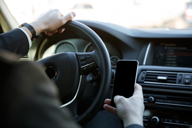 Hombre usando un teléfono móvil mientras conduce su automóvil