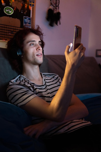 Foto hombre usando teléfono móvil mientras está sentado en el cuarto oscuro
