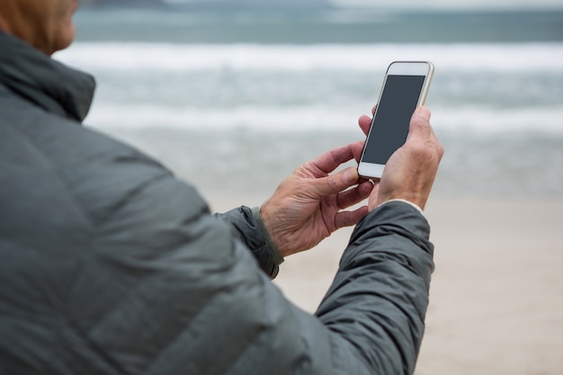 Hombre usando un teléfono móvil en la playa