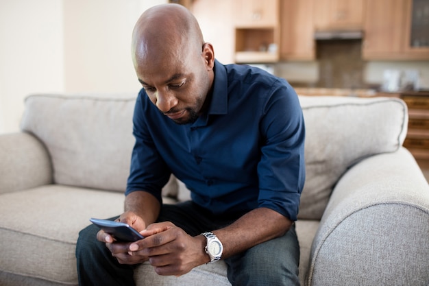 Hombre usando un teléfono móvil en la sala de estar