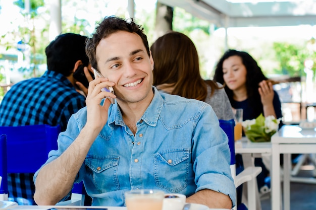 Hombre usando teléfono móvil y tomando café