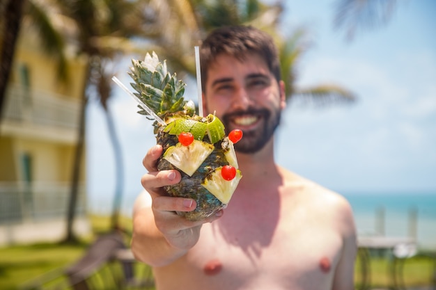 Hombre de vacaciones en risort bebiendo bebida dulce de piña.