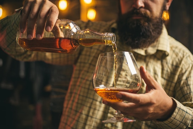 Hombre con vaso de brandy o coñac Hombre sosteniendo un vaso de whisky Retrato de hombre con vaso de whisky aislado en estudio negro