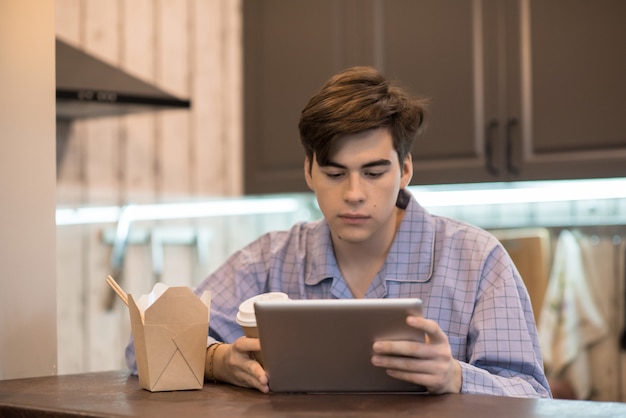 Hombre con vaso de plástico usando tableta