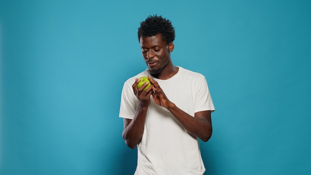 Hombre vegetariano jugando con manzana verde en estudio