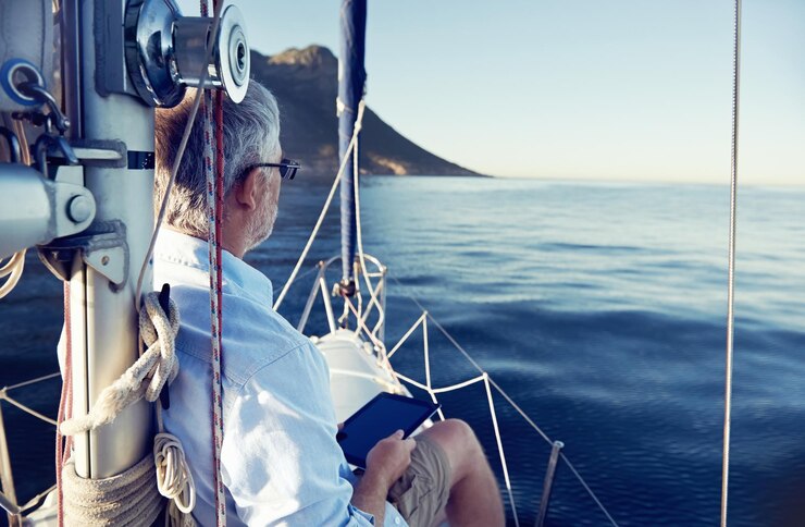 hombre de vela leyendo computadora tablet en un barco con tecnología moderna y un estilo de vida exitoso jubilado sin preocupaciones