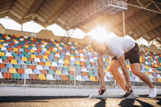 Foto hombre velocista entrenando en el estadio en pista de atletismo