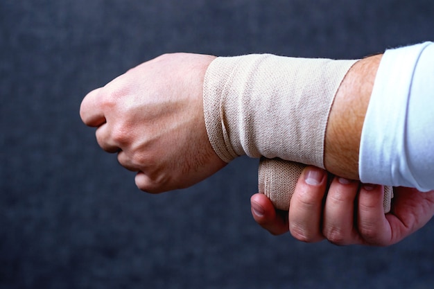 Un hombre venda su mano con una venda deportiva.